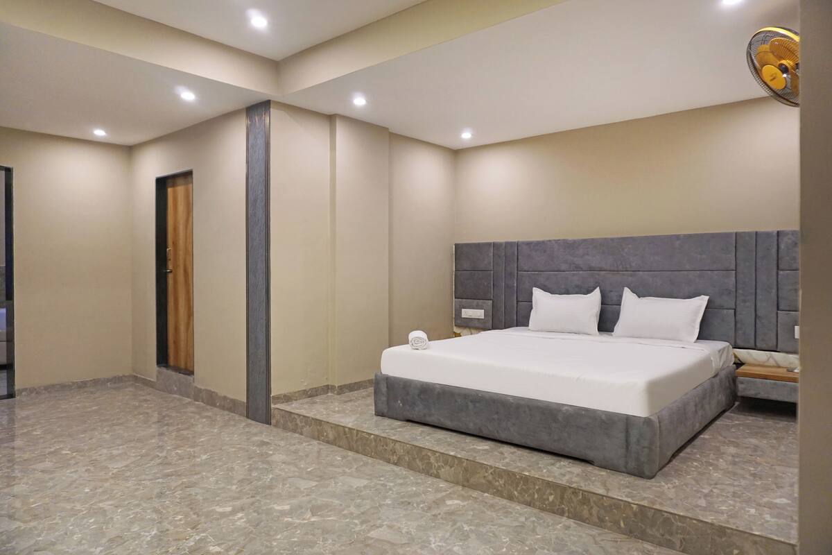 A modern hotel room with a large bed, a wooden door, and a marble floor.