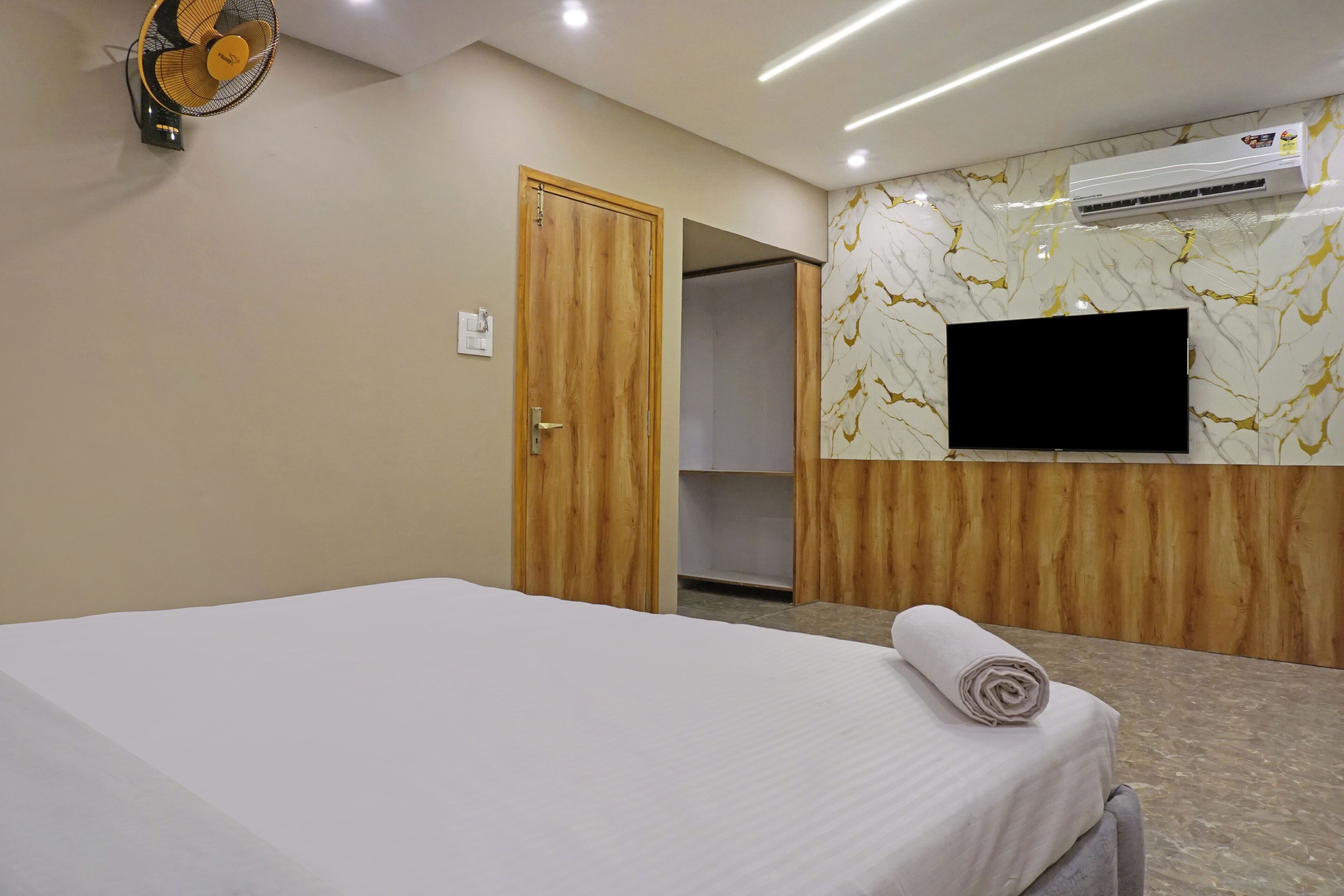 Una habitación de hotel con una cama, aire acondicionado, televisión y un armario de madera.