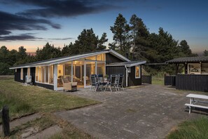 Une maison moderne dotĂ©e dâun patio, dâun espace salon extĂ©rieur et dâune zone abritĂ©e.