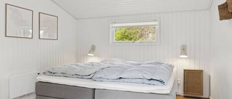 Quarto com cama, duas luminárias na parede, janela e radiador.