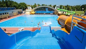 Ein Wasserpark mit großem Pool, Rutschen und überdachtem Bereich.