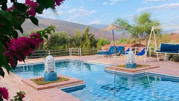 Ein Poolbereich mit zwei Pools, Liegestühlen und Bergblick.