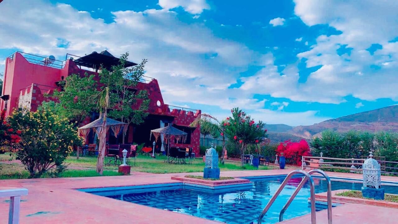 A pool area with a red building, a statue, and a clear sky.