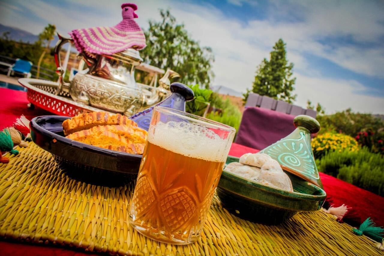 Una mesa con una cerveza, un plato de comida y un juego de té marroquí tradicional.
