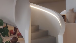 Un escalier moderne au design incurvé, avec des murs blancs et une verrière.