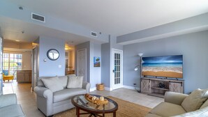 Un salon avec un canapé, une table basse et un téléviseur posé sur un meuble en bois.