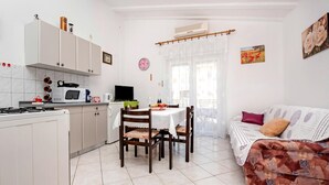A compact kitchen with white cabinets, a dining table with chairs, a sofa, and a TV. - Apartment in Rovinj near Fantasia Monfiorenzo (Rovinj)