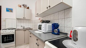 A kitchen with a stove, oven, microwave, coffee maker, and a kettle on the counter. - Apartment in Rovinj near Fantasia Monfiorenzo (Rovinj)