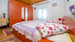 A bedroom with a wooden ceiling, a bed with floral pillows, a bedside table, and a mirror. - Apartment in Rovinj near Fantasia Monfiorenzo (Rovinj)