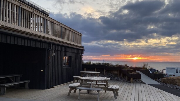 A wooden deck with picnic tables and benches, overlooking a sunset over the water. - The Corner House -  a house that sleeps 10 guests  in 4 bedrooms (Hopeman)