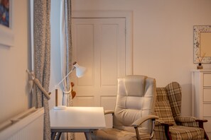 A room with a white door, a desk with a lamp, and two chairs. - Cosy Garden Cottage | Fleming Place (St Andrews)