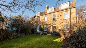 A stone building with a garden, a picnic table, and a small shed. - Cosy Garden Cottage | Fleming Place (St Andrews)