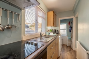 A kitchen with a sink, stove, and wooden cabinets. - Cosy Garden Cottage | Fleming Place (St Andrews)