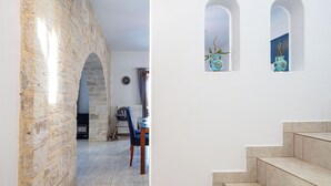 A stone archway leading to a dining area with a table and chairs, and a staircase with a view of the outside through arched windows. - Villa Delfi /w private pool, at a serene village (Agia Triada)