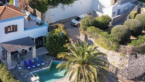 A villa with a swimming pool, outdoor seating, and a stone wall. - Villa Delfi /w private pool, at a serene village (Agia Triada)