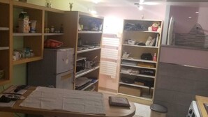 Una cocina compacta con estantes abiertos, un refrigerador y un comedor con una mesa y sillas.