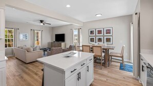 A modern living space with a kitchen, dining area, and a seating area with a sofa and chairs.
