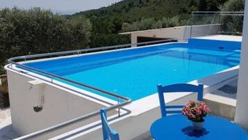 A rectangular pool with a blue interior, surrounded by a white deck and a metal railing.