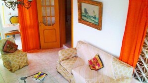 A living room with a sofa set, a dining table with chairs, a chandelier, and a door with a glass panel. - Villa Konaki (Grammatiko)