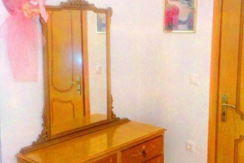 A wooden dresser with a mirror and a door.