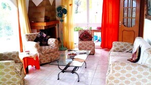 A living room with patterned sofas, a glass coffee table, and a fireplace. - Villa Konaki (Grammatiko)