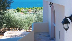 A coastal view with a clear sky, a sea, and a building with a white facade and a stone staircase. - Villa Konaki (Grammatiko)