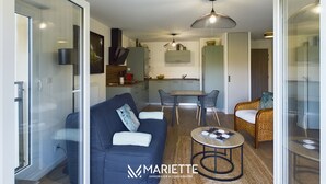 A modern living space with a sofa, dining table, chairs, and a kitchen area.