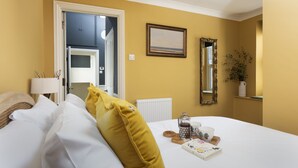 A hotel room with a bed, a bedside table with a lamp, a mirror, and a window with a view of the outside.