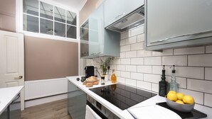 A modern kitchen with white cabinetry, a black stovetop, and a window above the sink.