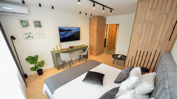 Ein modernes Schlafzimmer mit Bett, Schreibtisch und Fernseher.