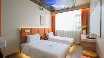 Habitación de hotel con dos camas, un escritorio, un espejo y un mural en el techo.