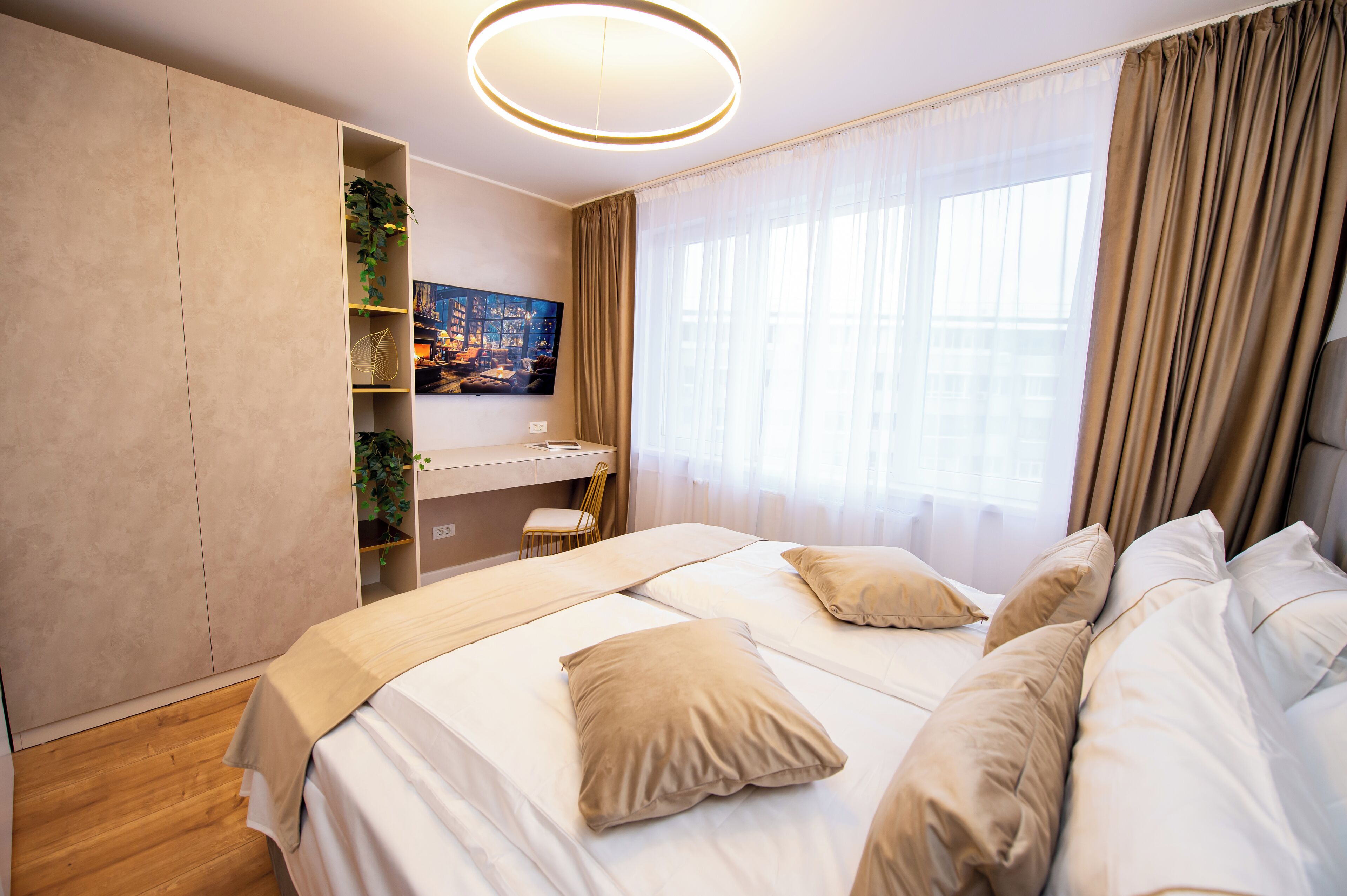 A modern bedroom with a large bed, a desk, and a wardrobe.