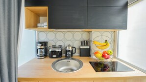 A modern kitchen with a built-in sink, a coffee maker, a toaster, and a fruit basket. - One by One - Adam's Studio - Cismigiu Gardens (București)