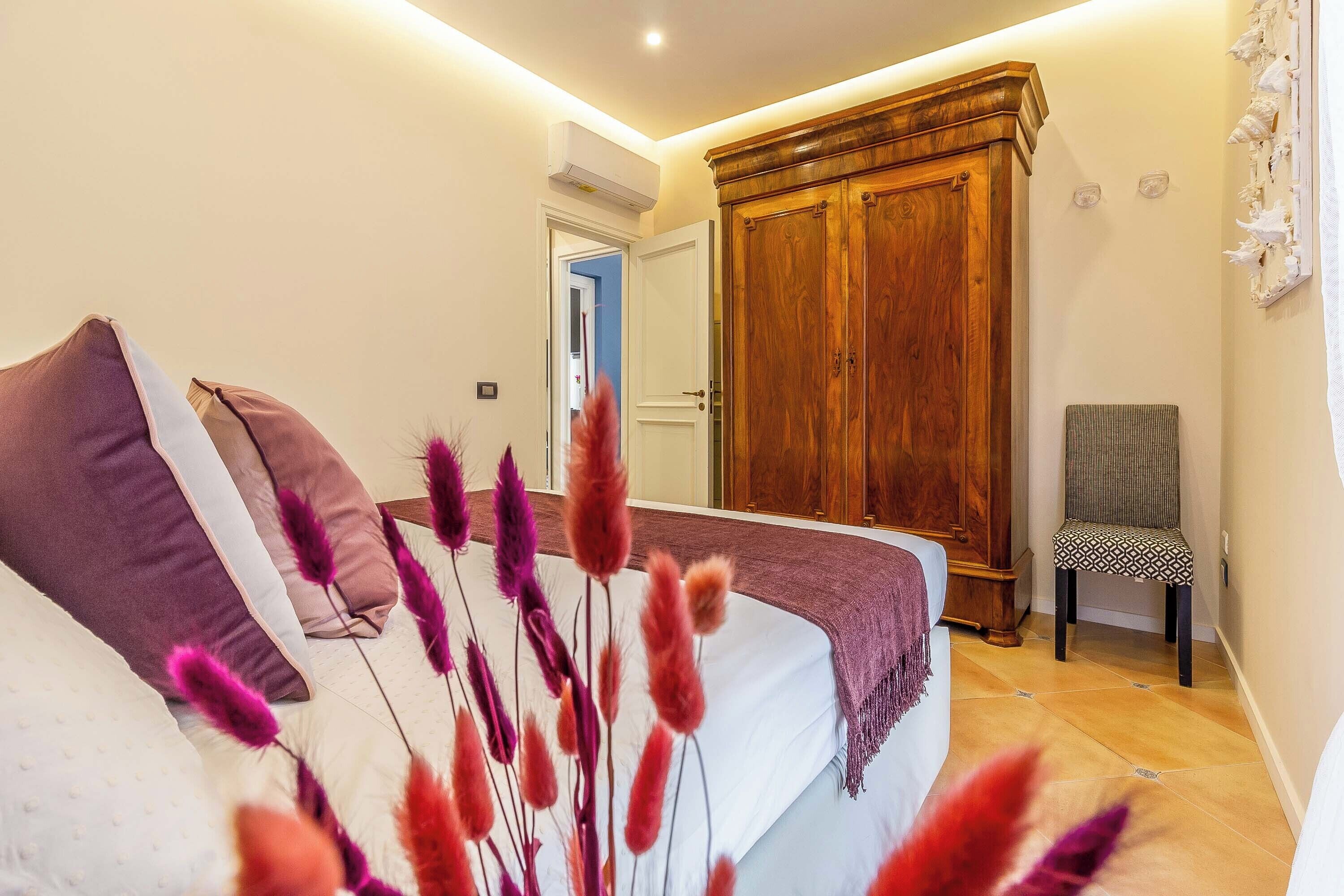 A bedroom with a bed, pillows, a chair, and a wardrobe.