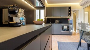 Cozinha moderna com uma ilha grande, eletrodomésticos embutidos e um espaço de estar com uma cadeira estampada.