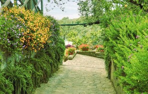 Un vialetto in pietra costeggiato da rigogliosa vegetazione e piante fiorite.