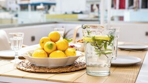 A table with a bowl of lemons, a pitcher of water with mint, and a glass of water. - Olia Boutique Apartments (Karpathos)