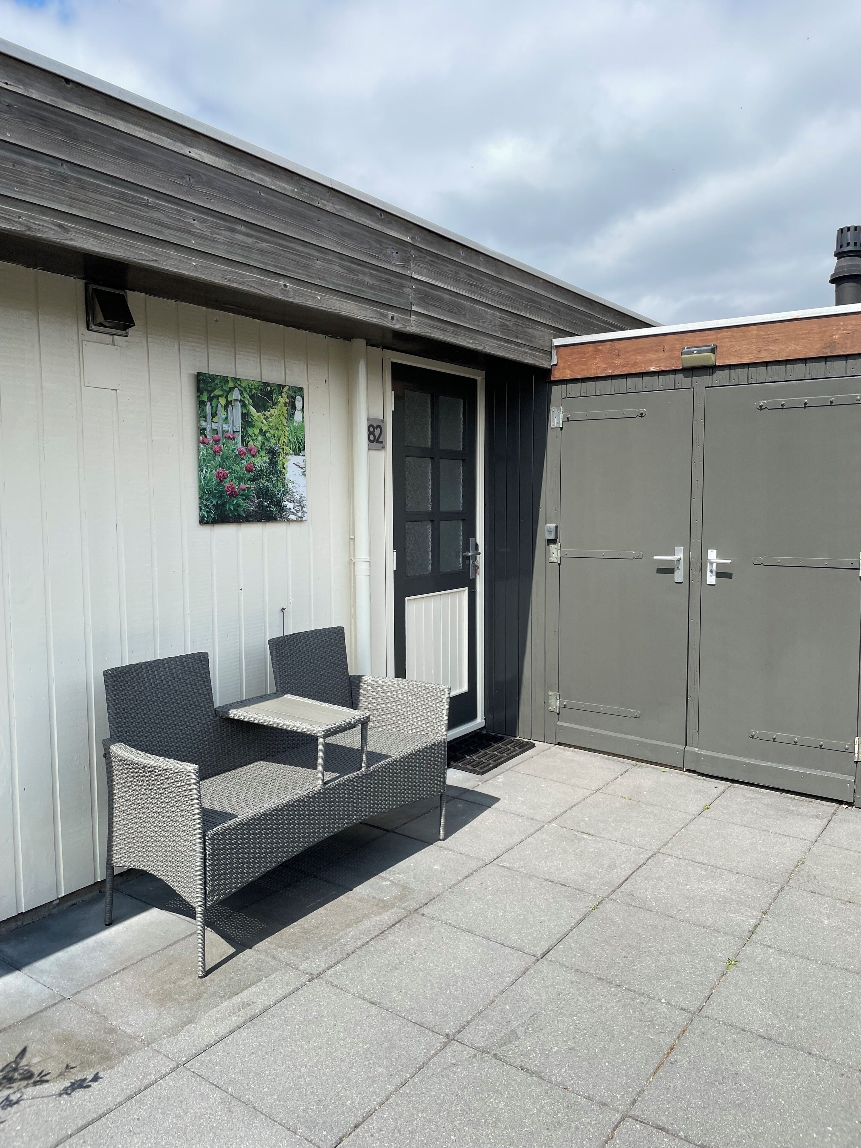 A patio with wicker furniture, a door with frosted glass panels, and a grey metal gate.