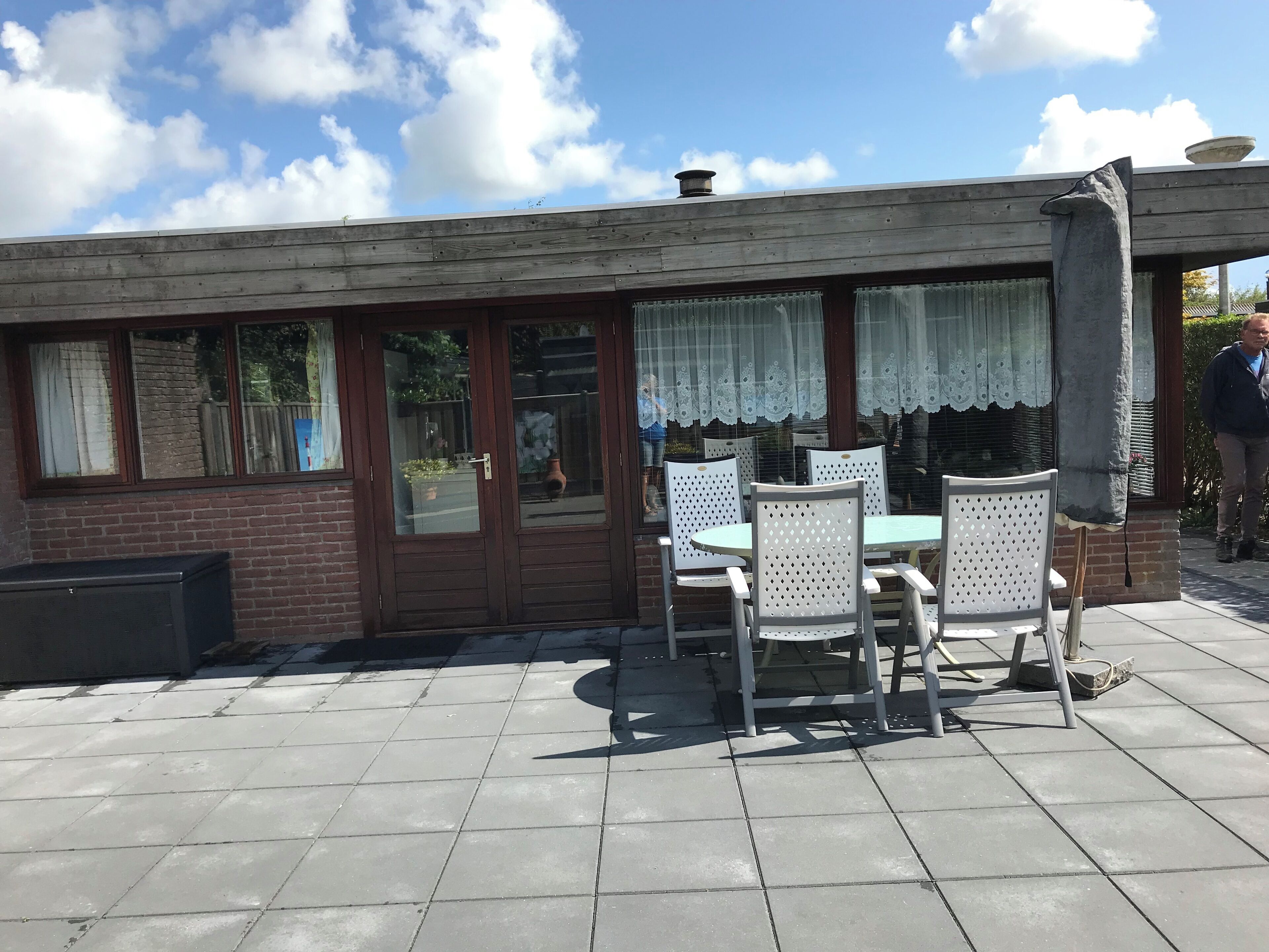 Een terras met een tafel en stoelen, een bakstenen muur en een houten dak.