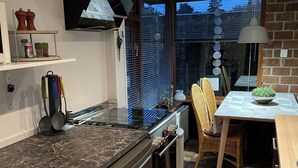 A modern kitchen with a built-in oven, a dishwasher, and a dining area with a table and chairs. - Sunny house close to the dunes and the sea. Families with children and dogs. (Warmenhuizen)