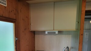 A compact kitchen with a washing machine, a sink, and wooden cabinets.