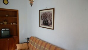 A living room with a plaid sofa, a television on a wooden cabinet, a framed picture on the wall, and a small table with a lamp. - House El Cardón B2 in Buenavista del Norte (Buenavista del Norte)