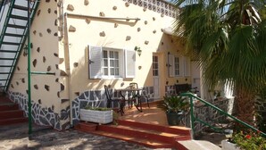 A building with a stone facade, a staircase, a patio with a table and chairs, and a palm tree. - House El Cardón B2 in Buenavista del Norte (Buenavista del Norte)