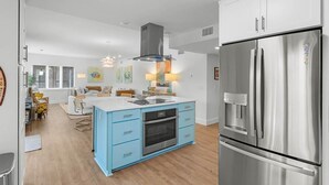 A modern kitchen with a central island, stainless steel appliances, and light blue cabinetry. - Fun and Sun 2nd Floor Oceanview 3 Bedroom (Pawleys Island)