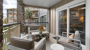 A balcony with outdoor seating, a potted plant, and a view of neighboring buildings. - Fun and Sun 2nd Floor Oceanview 3 Bedroom (Pawleys Island)