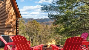 A log cabin with a fire pit and red Adirondack chairs. - This cabin is a 3 bedroom(s), 1 bathrooms, located in Sevierville, TN. (Sevierville)