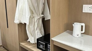 Une chambre d’hôtel équipée d’une armoire en bois, d’un four à micro-ondes, d’une bouilloire et d’un plan de travail.