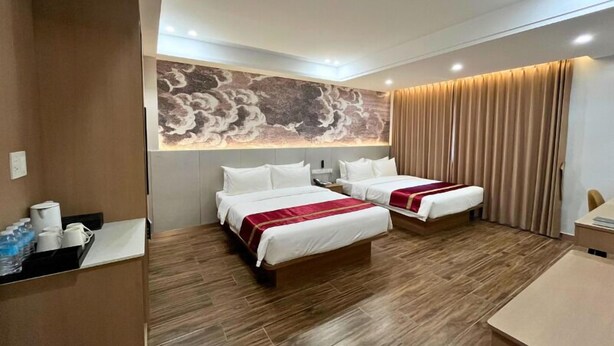 Une chambre d’hôtel avec deux lits, un plancher en bois, une fresque murale et un bureau avec une chaise.