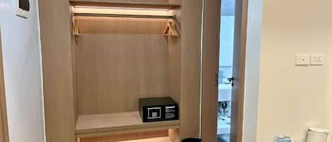 Un vestidor con estantes de madera, una caja de almacenamiento negra y un cubo de basura.