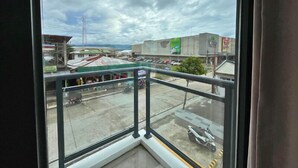 Une vue depuis un balcon donnant sur un parking, avec un immeuble en arrière-plan.